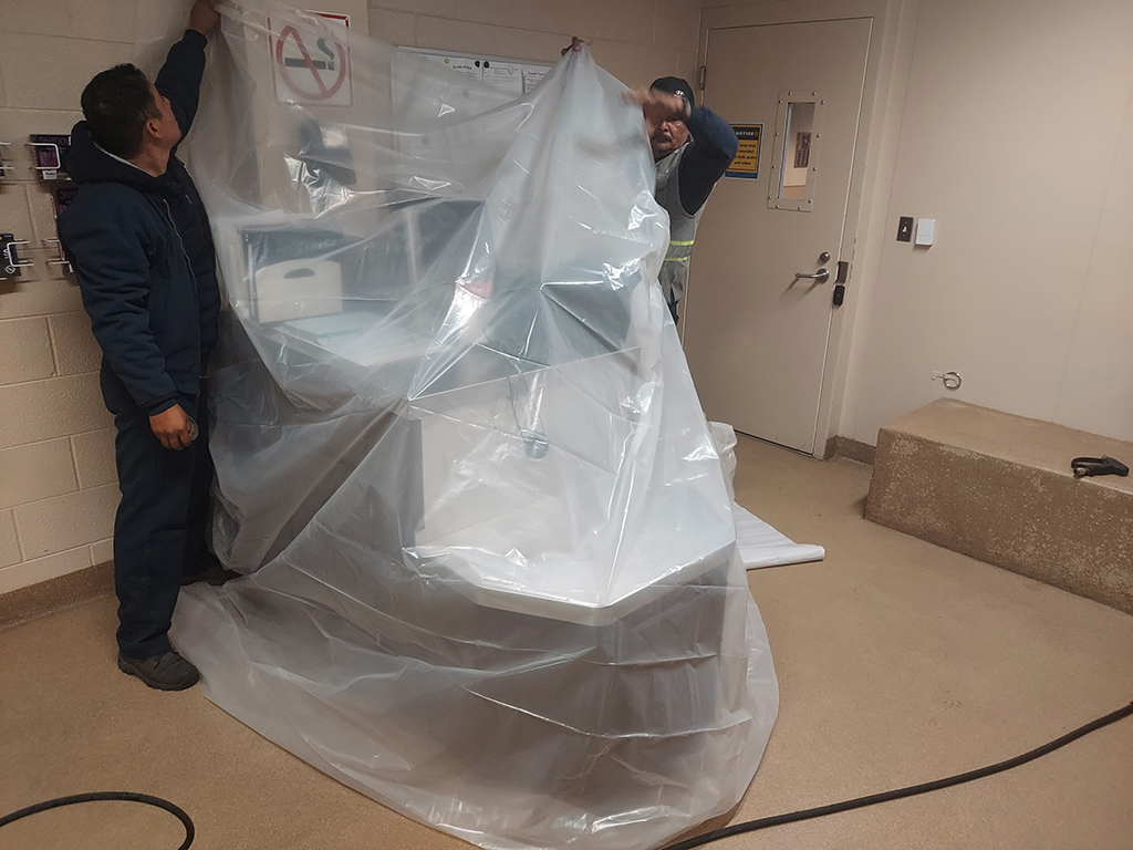 Cleaning the holding cells at the Littleton, Colorado Police Department starts with using plastic and tape to cover all electronic equipment, bulletin boards, and other items that could be damaged by water spray.